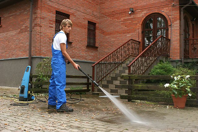 workman removing driveway stains by pressure washing